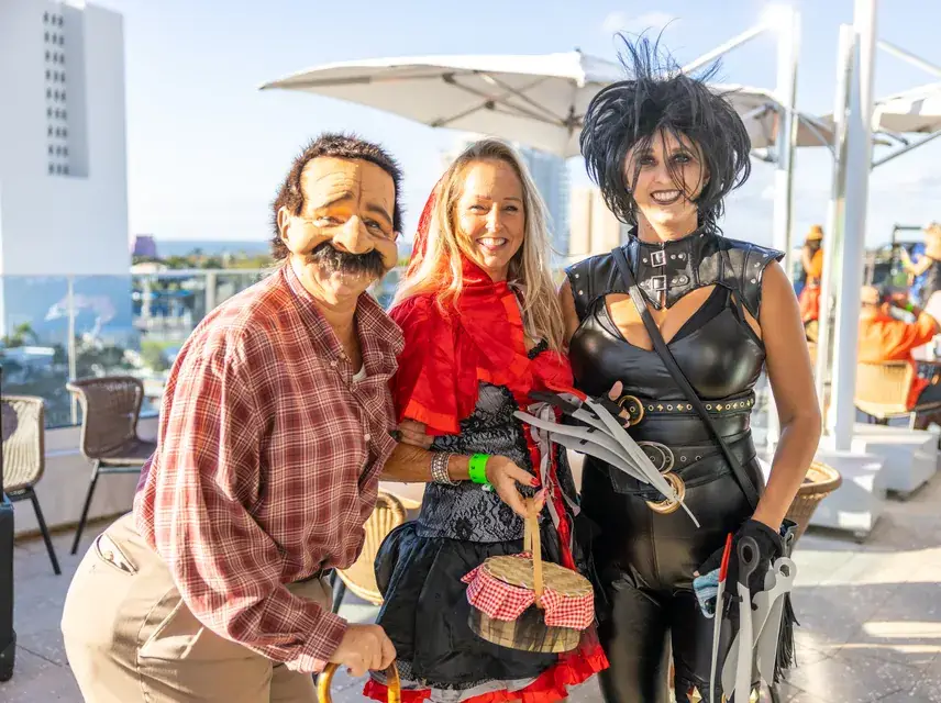 Three crawlers in costume on a sunny rooftop bar at Halloween